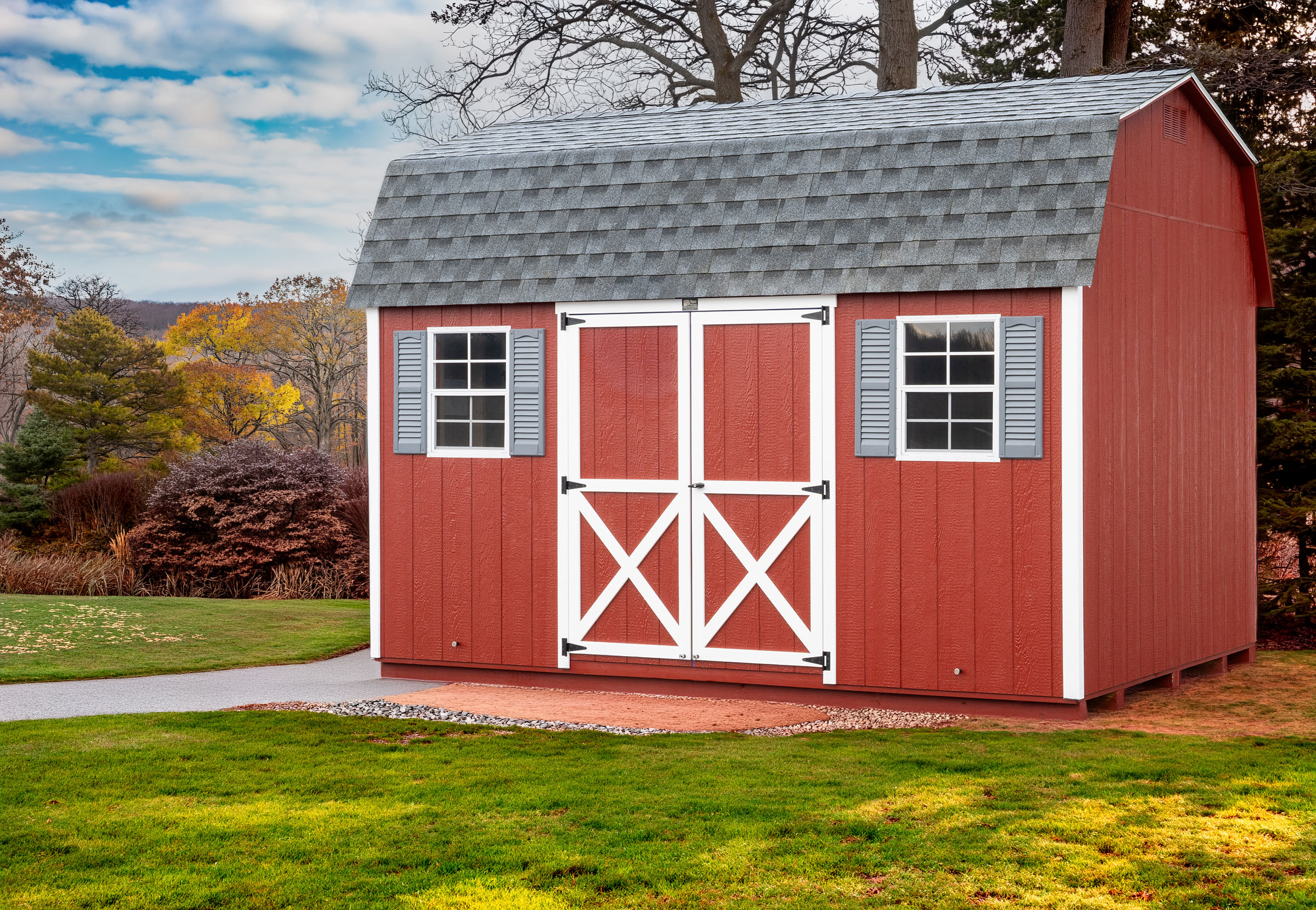 A 10x14 Mast Mini Barn Dutch Barn shed shown in Stauffer Red with White trim and shingle roof