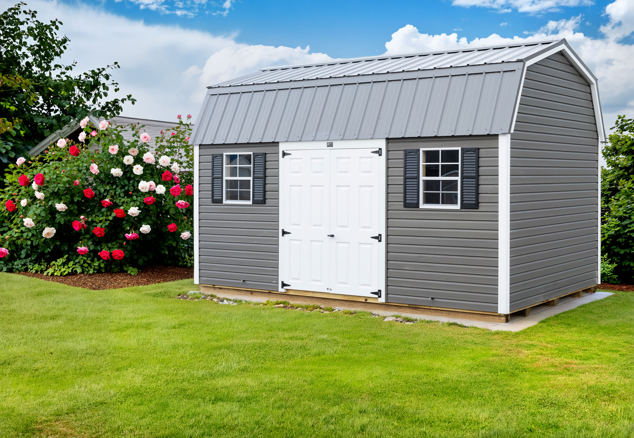 A 10x16 Mast Mini Barn Dutch Barn shed shown in Charcoal Smoke vinyl siding with White trim, white fiberglass slab doors, and a grey metal roof