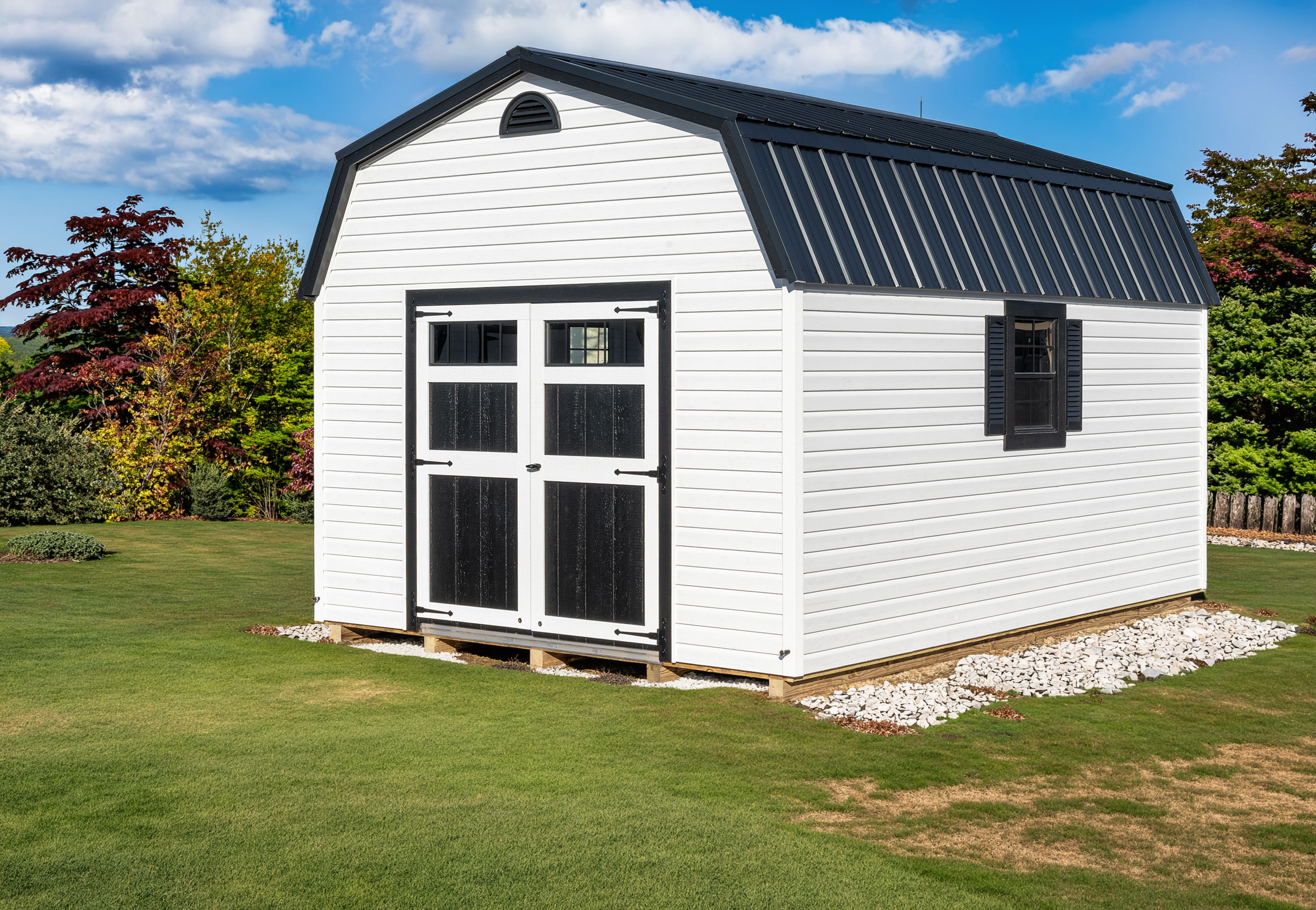 A 12x16 Mast Mini Barn Dutch Barn shed shown in white vinyl siding with Black trim and black metal roof