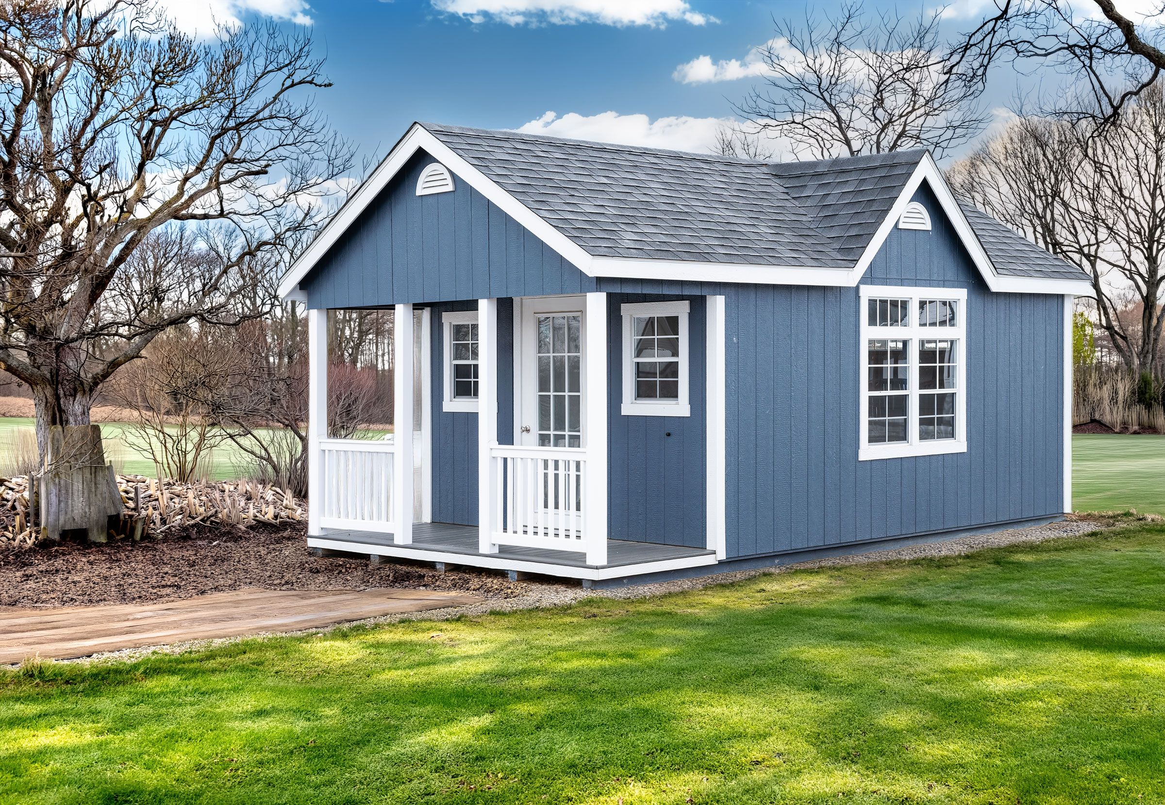 A 12x20 Mast Mini Barn Cape Cod shed shown in Navy Blue with White trim, 4ft end porch, Chalet dormer, deluxe trim package