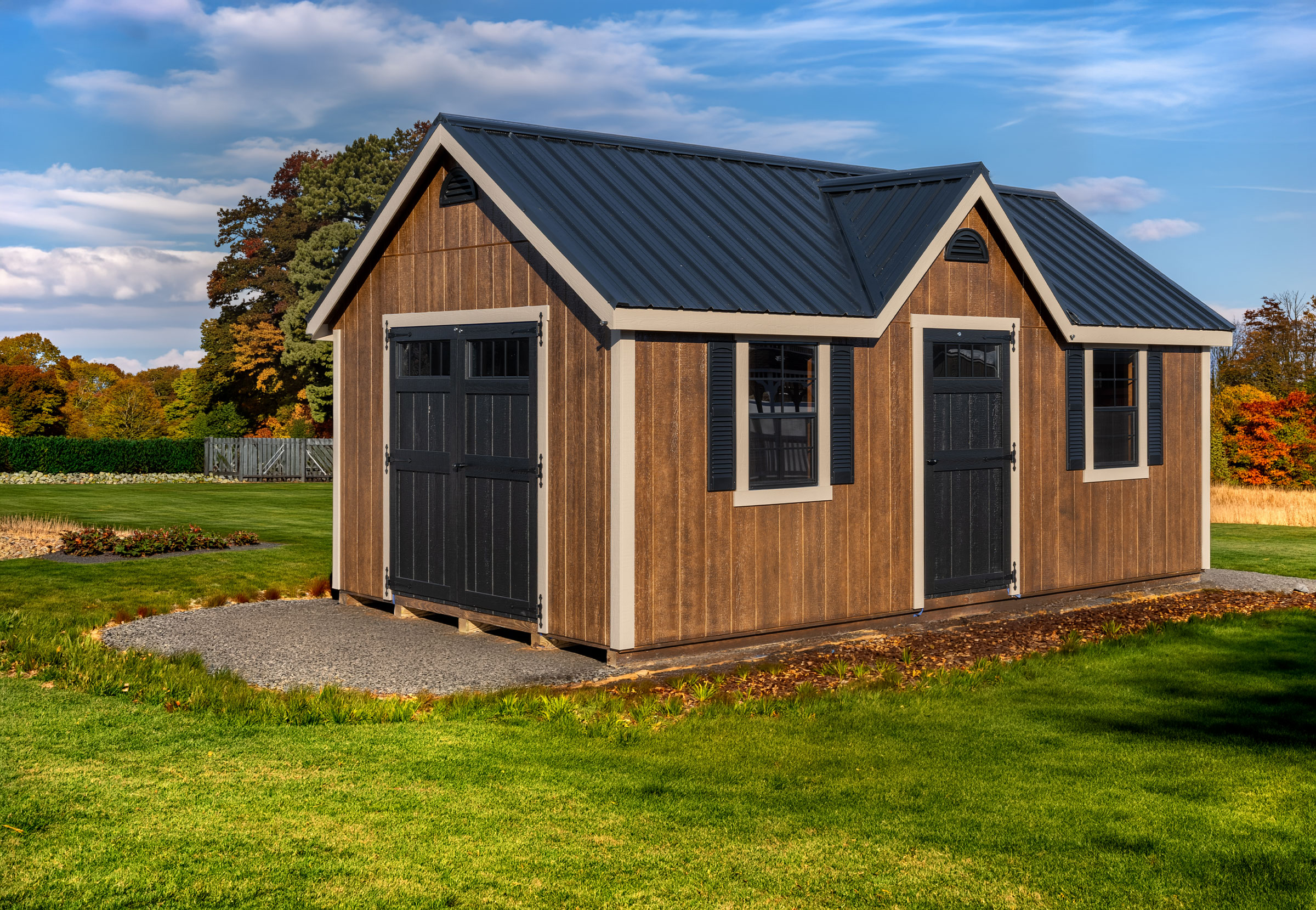 A 12x20 Mast Mini Barn Chalet shed shown in Chestnut Brown Urethane with Tuscan Clay trim, Black doors and windows, deluxe trim package
