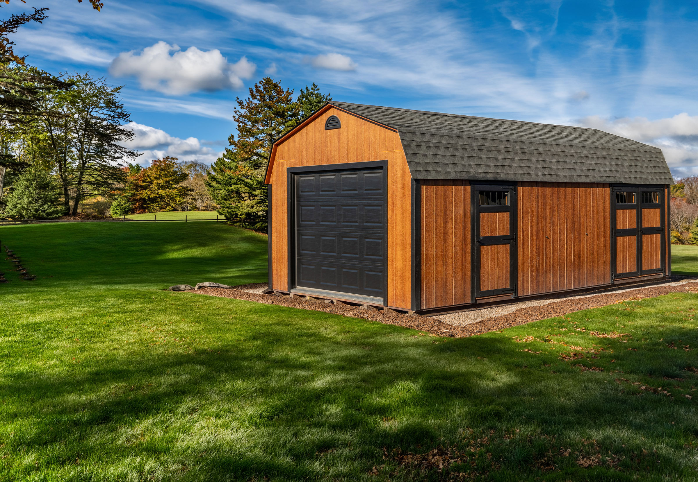 A 14x24 Mast Mini Barn Garage shown in Butternut Urethane with Black trim, deluxe package